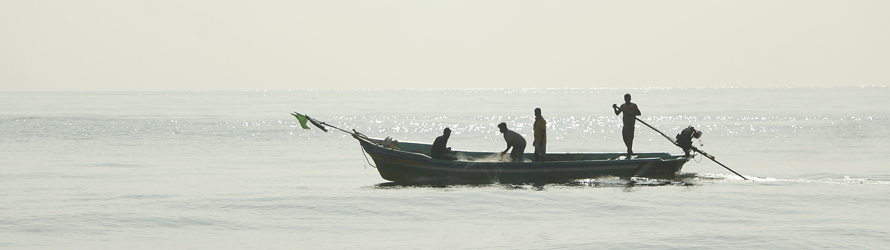 Fishermen in a small boat casting nets